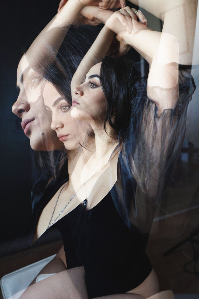 Valeria Cisneros a model is captured in a multi-layered artistic portrait. The image showcases her in various poses with overlapping images of her face and upper body. The color palette is muted with a focus on blacks whites and grays giving it a contemporary and sophisticated feel.